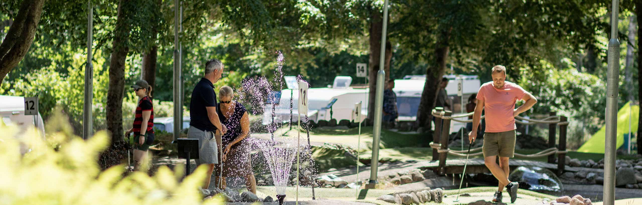 Campinggäster som spelar minigolf.